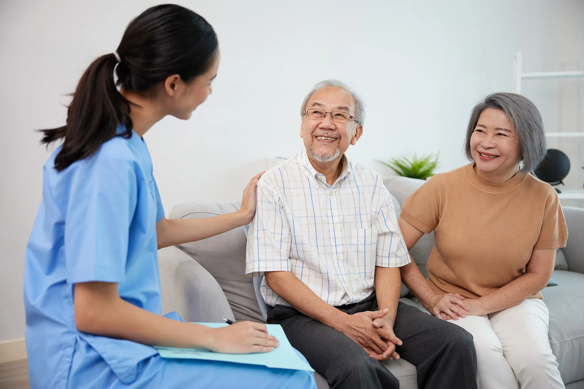 A caregiver meeting with an older couple in their living room to discuss their care.